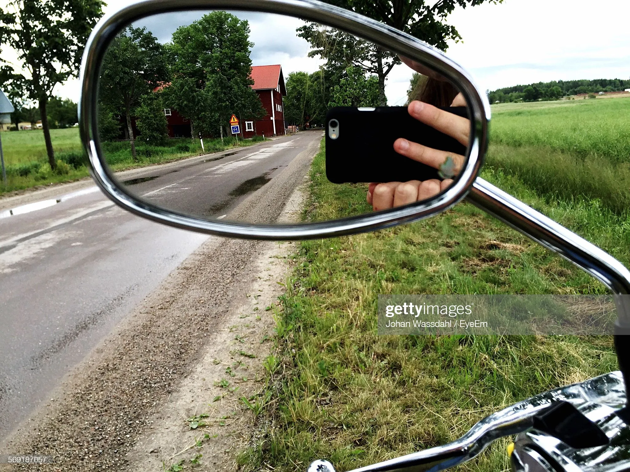 Reflection of cropped man photographing through smart phone on side-view mirror : Stock Photo